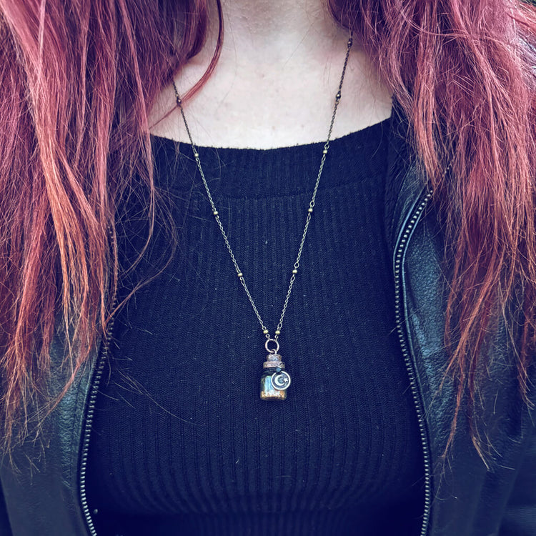 bewitch // mini spell jar glass bottle pendant necklace worn on model by Peacock and Lime