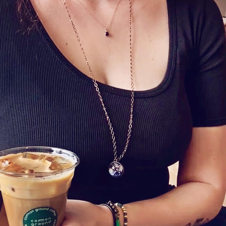 out of this world // glow in the dark bright universe sphere pendant necklace worn on model with other jewelry by peacock & lime