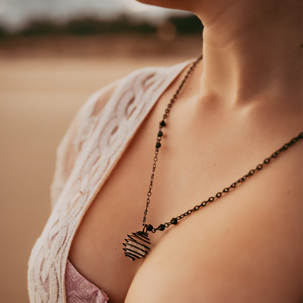encapsulate / caged crystal gemstone necklace worn on model at the beach - close up - Peacock & Lime